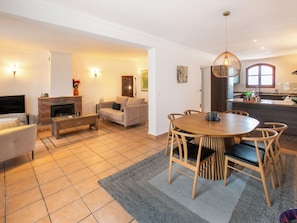 A living room with a fireplace, sofa, coffee table, and dining area with chairs and a table.
