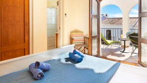 Ein Schlafzimmer mit Bett, einem Sessel und einem Balkon mit Tisch und Stühlen.