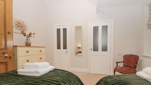 A bedroom with two beds, a dresser, a chair, and two doors.