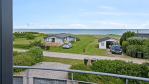 Ein Küsten-Campingpark mit mehreren kleinen Häusern, einem Kiesweg und Blick auf das Meer.