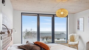 Ein modernes Schlafzimmer mit einem großen Bett, einer Holzbalkendecke und Blick ins Freie.