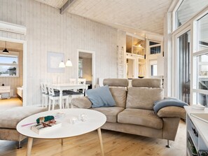 A modern living room with a sofa, a coffee table, and a dining area with chairs and a table.