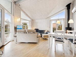 Een ruime zithoek met een bank, stoelen en een eettafel.