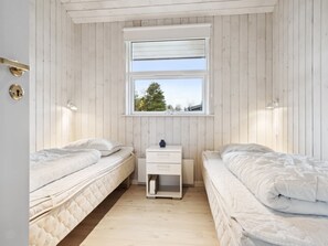 Een kamer met twee bedden, een klein nachtkastje, een raam met uitzicht en houten wanden.