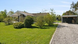 Een modern huis met een overdekte veranda, een grindpad en een kleine schuur.