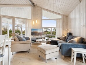 A spacious living room with a large window, a sofa set, a coffee table, and a television.