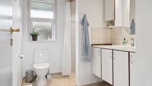 Een moderne badkamer met toilet, wastafel en spiegel.