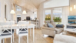Een ruime woonkamer met een eettafel, stoelen, een bank en een televisie.
