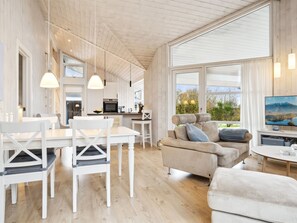 Un grand espace de vie comprenant une table à manger, des chaises, un canapé et un téléviseur.