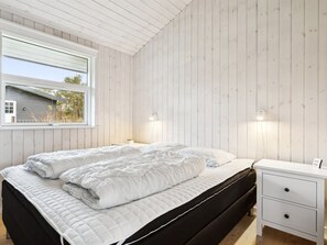 A bedroom with a bed, bedside tables, and a window.