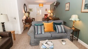 A living room with a grey sofa, a brown leather chair, a coffee table with books, and a lamp on a side table.