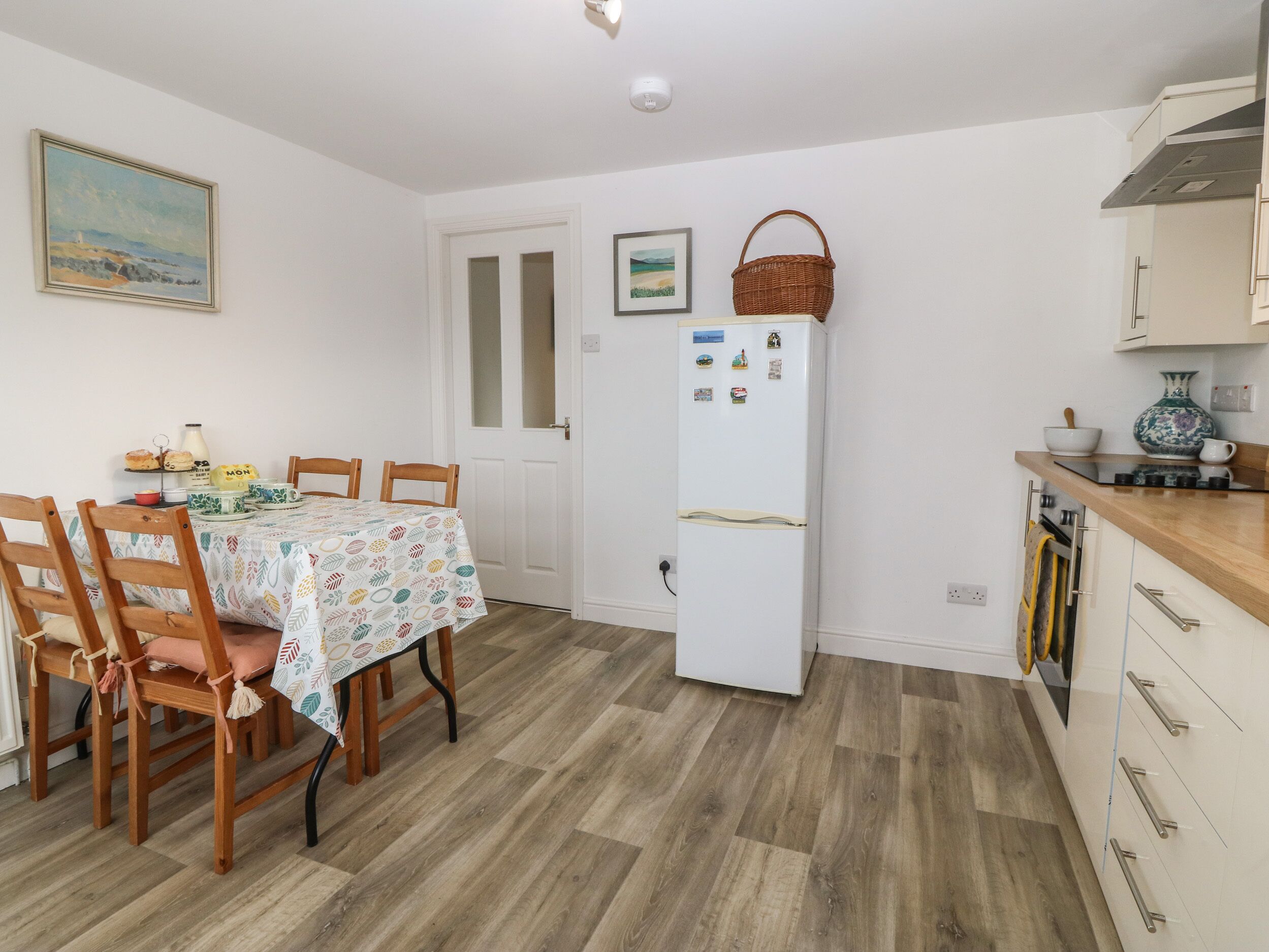 A compact kitchen with a white refrigerator, wooden cabinets, and a dining area with a table set for two.