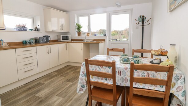 A kitchen with wooden cabinets, a microwave, and a dining table with chairs.