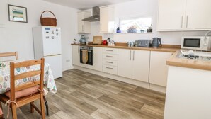 A modern kitchen with white cabinets, a wooden countertop, a built-in oven, and a microwave.