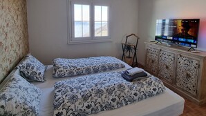 Ein Zimmer mit zwei Betten, einem Fernseher und einem Fenster.