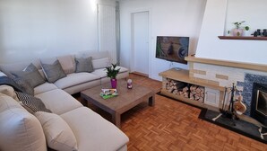 Ein modernes Wohnzimmer mit einer Couch, einem Couchtisch, einem Kamin und einem Fernseher.