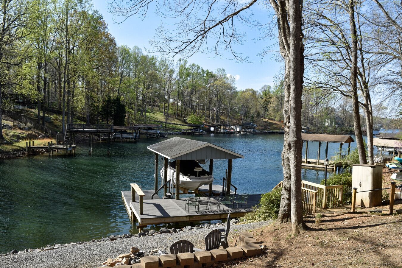 Un muelle a orillas del lago con un área de estar cubierta, un pequeño pabellón y un acceso para embarcaciones.