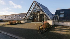 Un bâtiment moderne doté d’une façade en verre et d’un toit en pente.