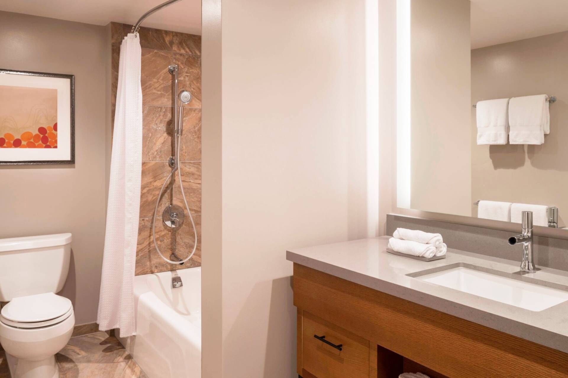 Een moderne badkamer met toilet, douche en wastafel.