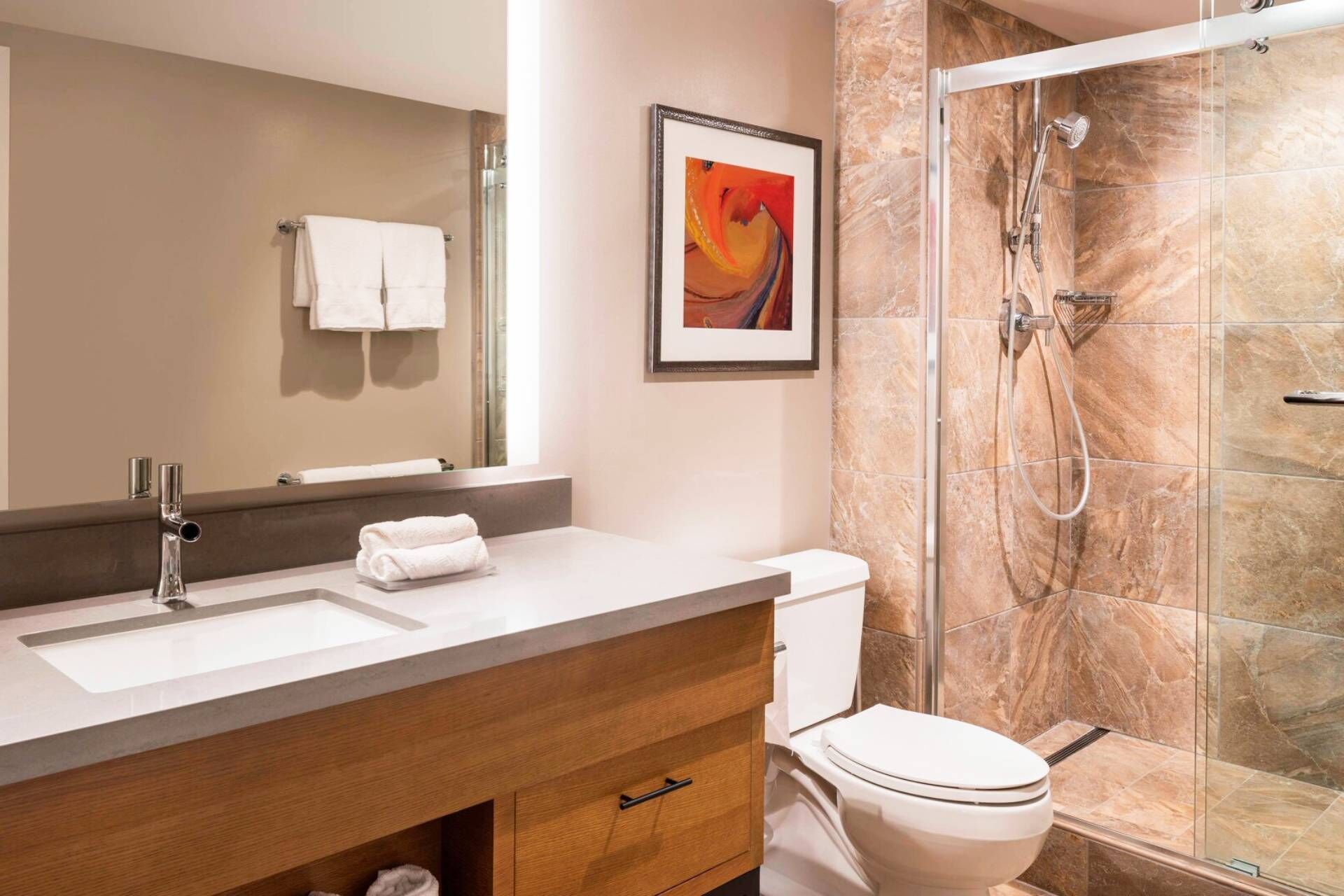 Une salle de bain moderne équipée d’un lavabo, d’un miroir, de toilettes et d’une douche.