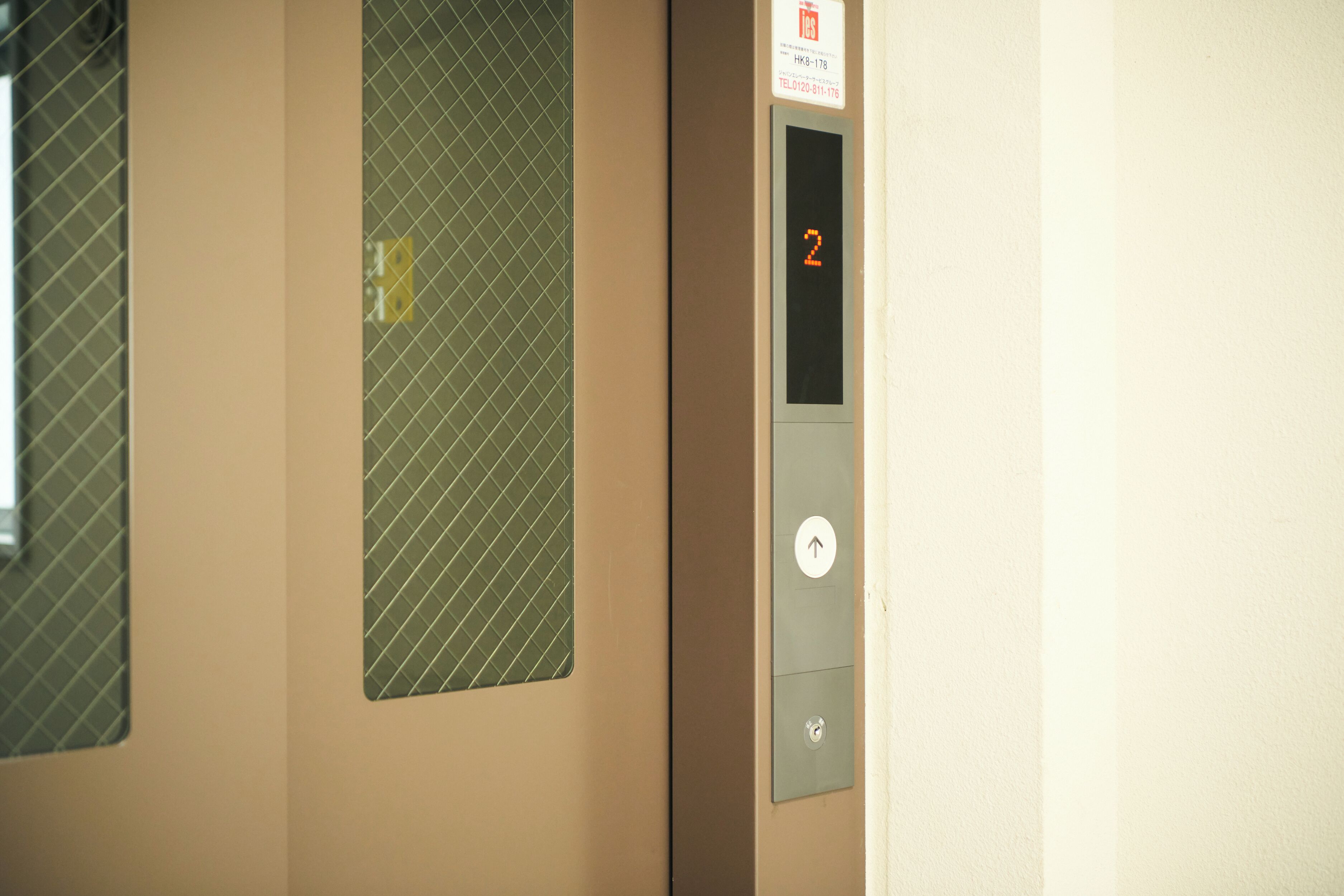 An elevator interior with a digital display showing the number 2, a door with a safety sign, and a keypad.