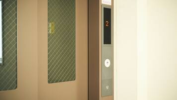 An elevator interior with a digital display showing the number 2, a door with a safety sign, and a keypad.