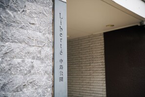 A vertical sign with the text "Liberte 中島公園" on a stone wall. - Residence Hotel Liberte (Sapporo)