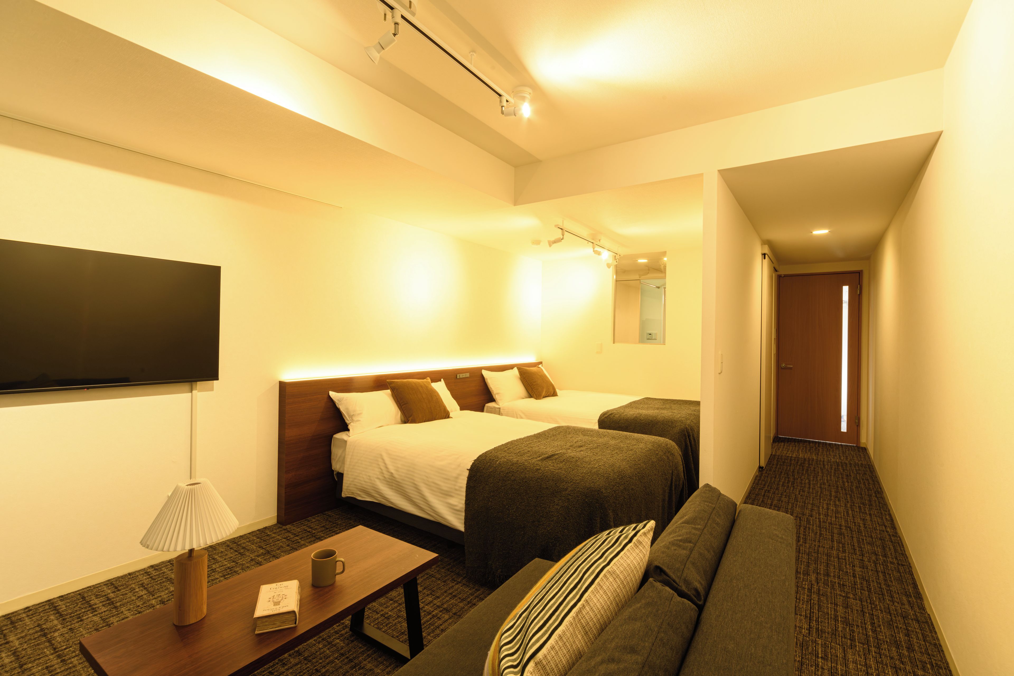 Une chambre d’hôtel comprenant un lit, un canapé, une table de chevet avec une lampe et un téléviseur à écran plat.