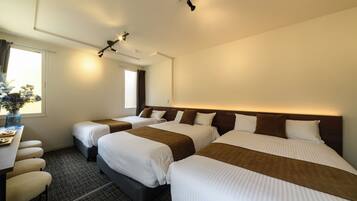 A hotel room with three beds, a desk, and a window.