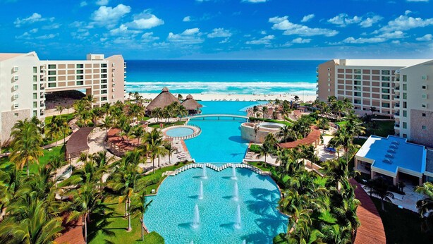 A resort with a central pool, palm trees, and a view of the ocean. - Westin Lagunamar Ocean Resort - Luxurious 1-Bedroom Villa - Family Friendly Resort! (Cancun)