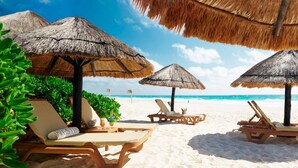 A beach with thatched umbrellas, lounge chairs, and a clear view of the ocean. - Westin Lagunamar Ocean Resort - Luxurious 1-Bedroom Villa - Family Friendly Resort! (Cancun)