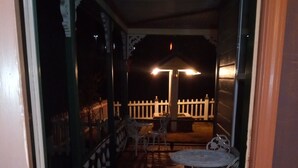 A covered outdoor seating area with a table and chairs, a white picket fence, and a wooden floor. - All Season's Groveland Inn  (Groveland)