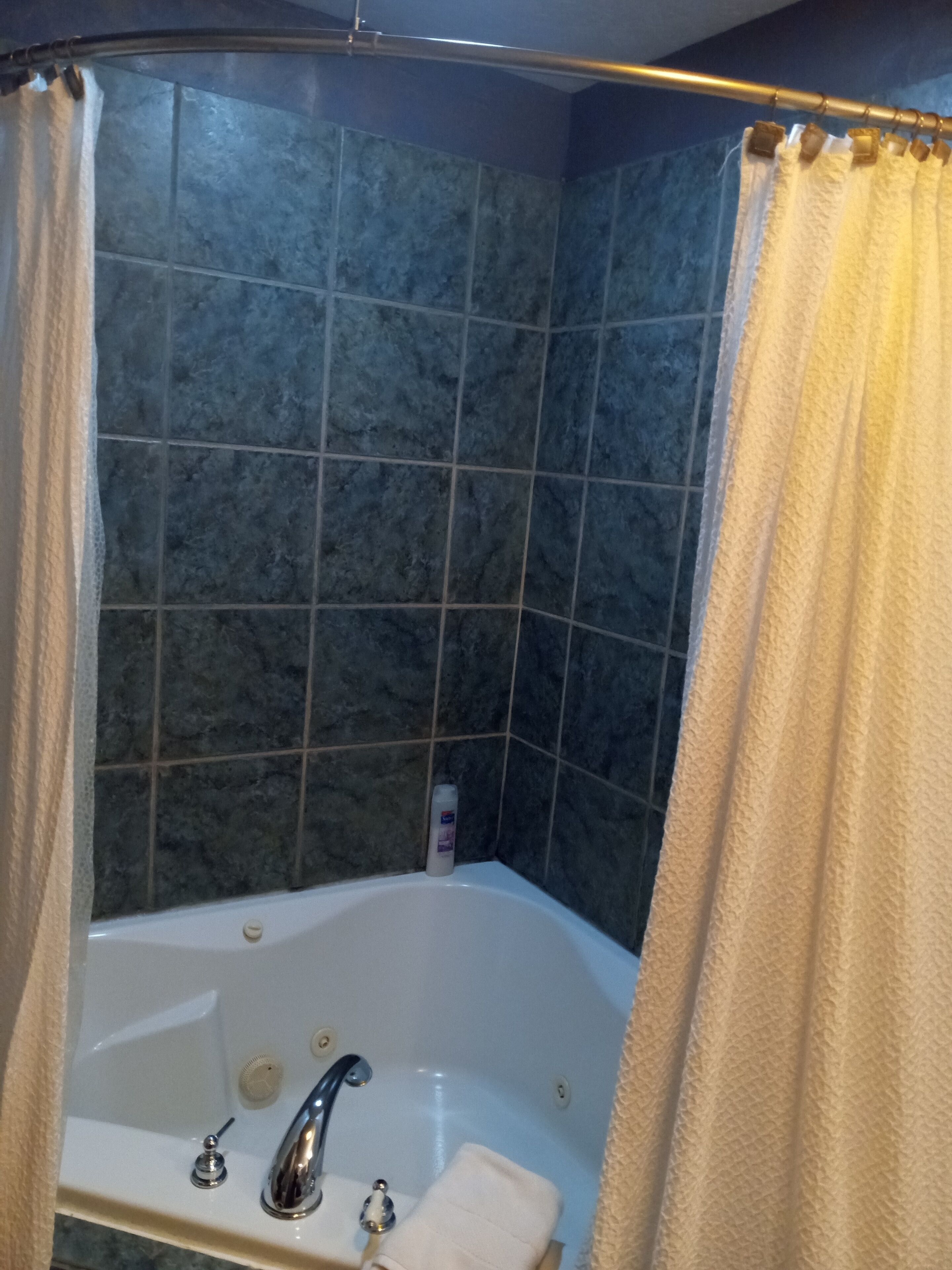 Un baño con bañera, cortina de ducha y paredes con azulejos.