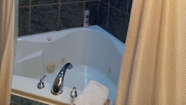 A bathroom with a bathtub, a shower curtain, and tiled walls. - All Season's Groveland Inn  (Groveland)