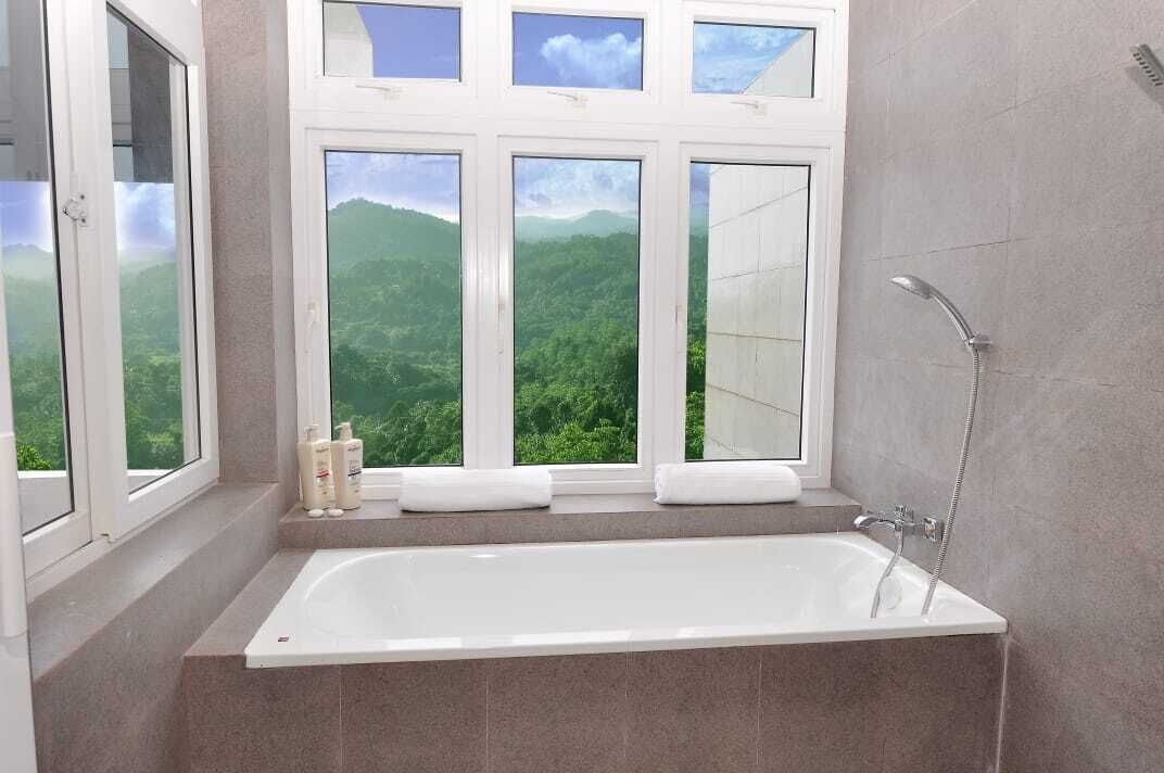 A bathroom with a bathtub, a shower, and a window with a mountain view.