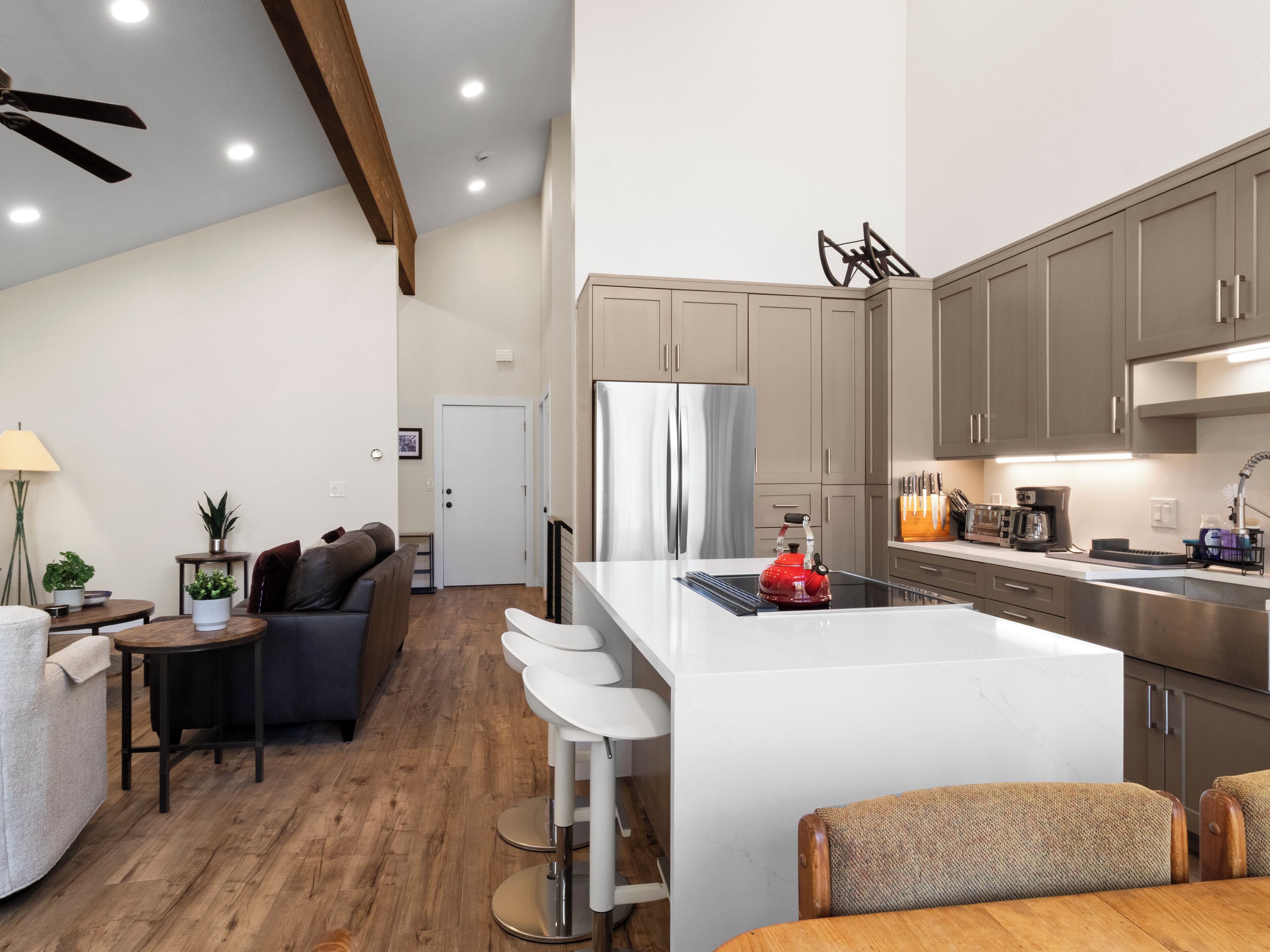 A modern kitchen with a central island, stainless steel appliances, and a dining area with bar stools.