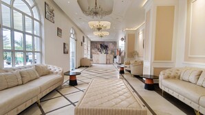 A spacious lobby with a central ottoman, plush sofas, and a chandelier. - Jewels Resorts (Jaipur)