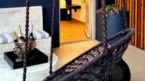A room with a hanging chair, a bed with a striped pillow, a sign reading "DE LUXE 1", and a small table with bottles. - Maison Pjure Boutique Hotel & Spa ( Adults Only ) (Montagu)