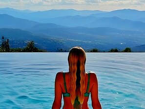 Una persona en una piscina con un paisaje montañoso al fondo.