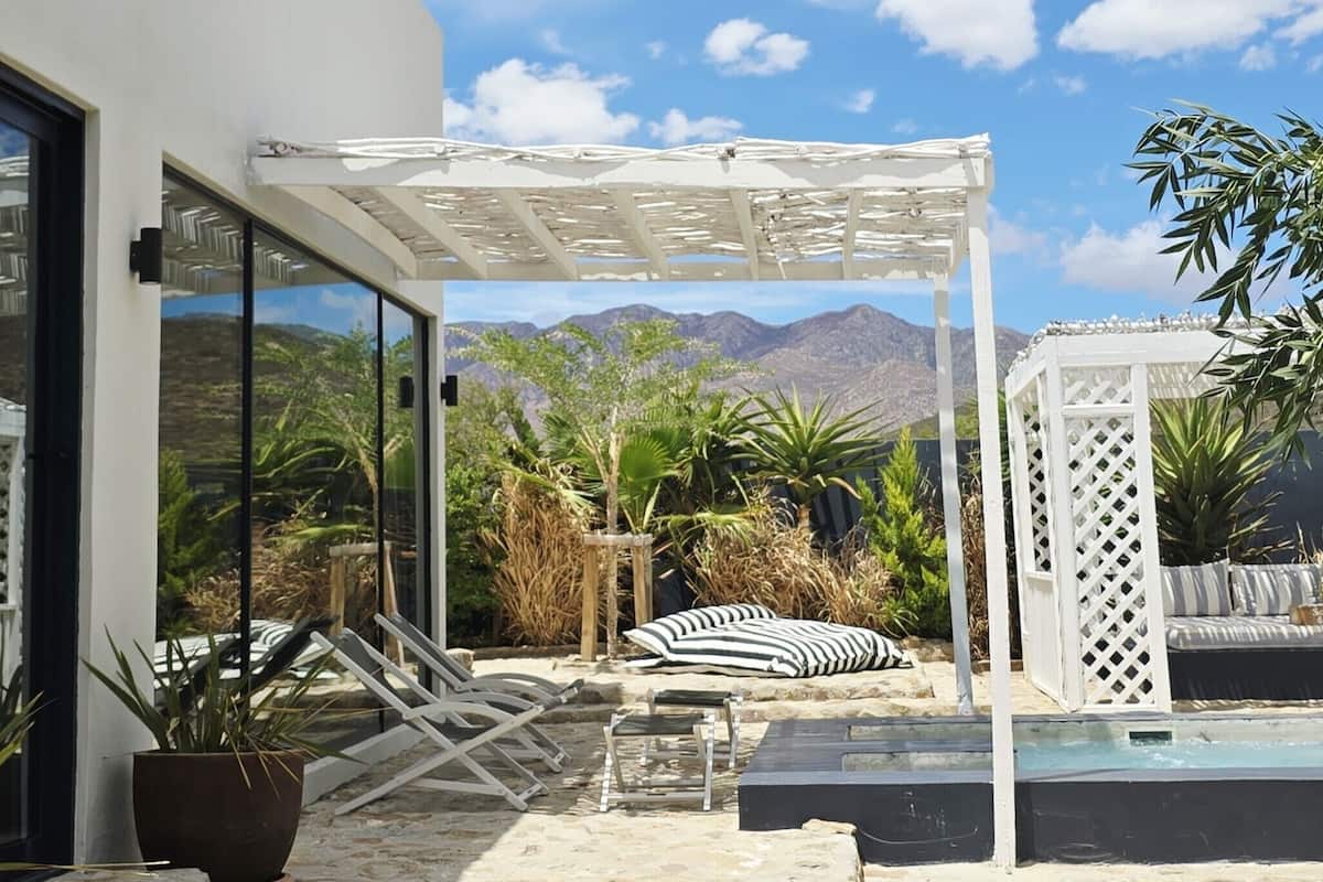 A patio with a pool, lounge chairs, and a pergola.