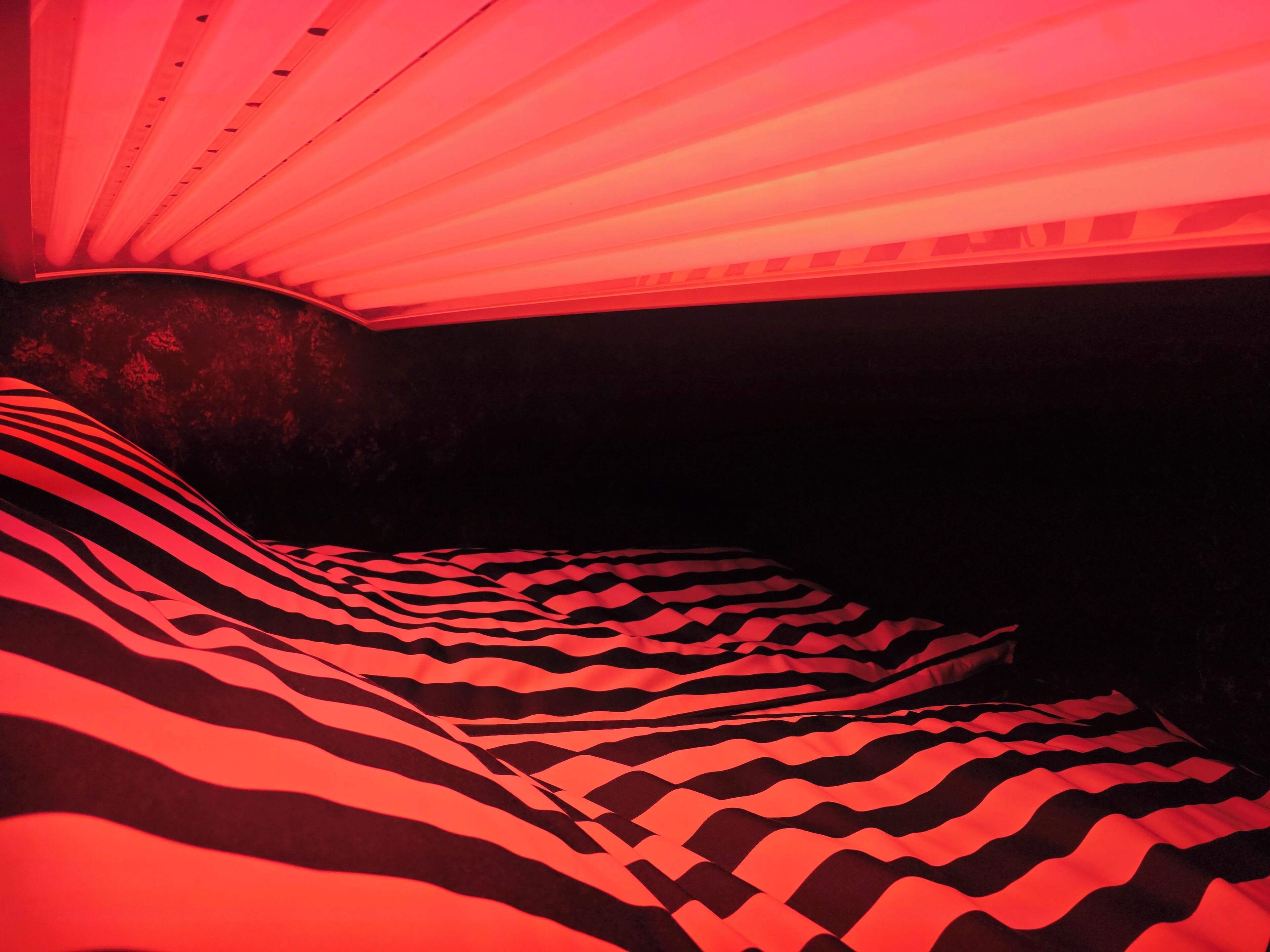 Una habitación con una colcha estampada y un techo con luminarias lineales.