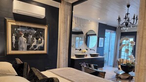 A modern hotel room with a large bed, a desk, a vanity with a mirror, and a chandelier. - Maison Pjure Boutique Hotel & Spa ( Adults Only ) (Montagu)