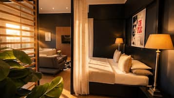 Ett modernt hotellrum med en säng, sänglampor, en tv och ett stort fönster med persienner.