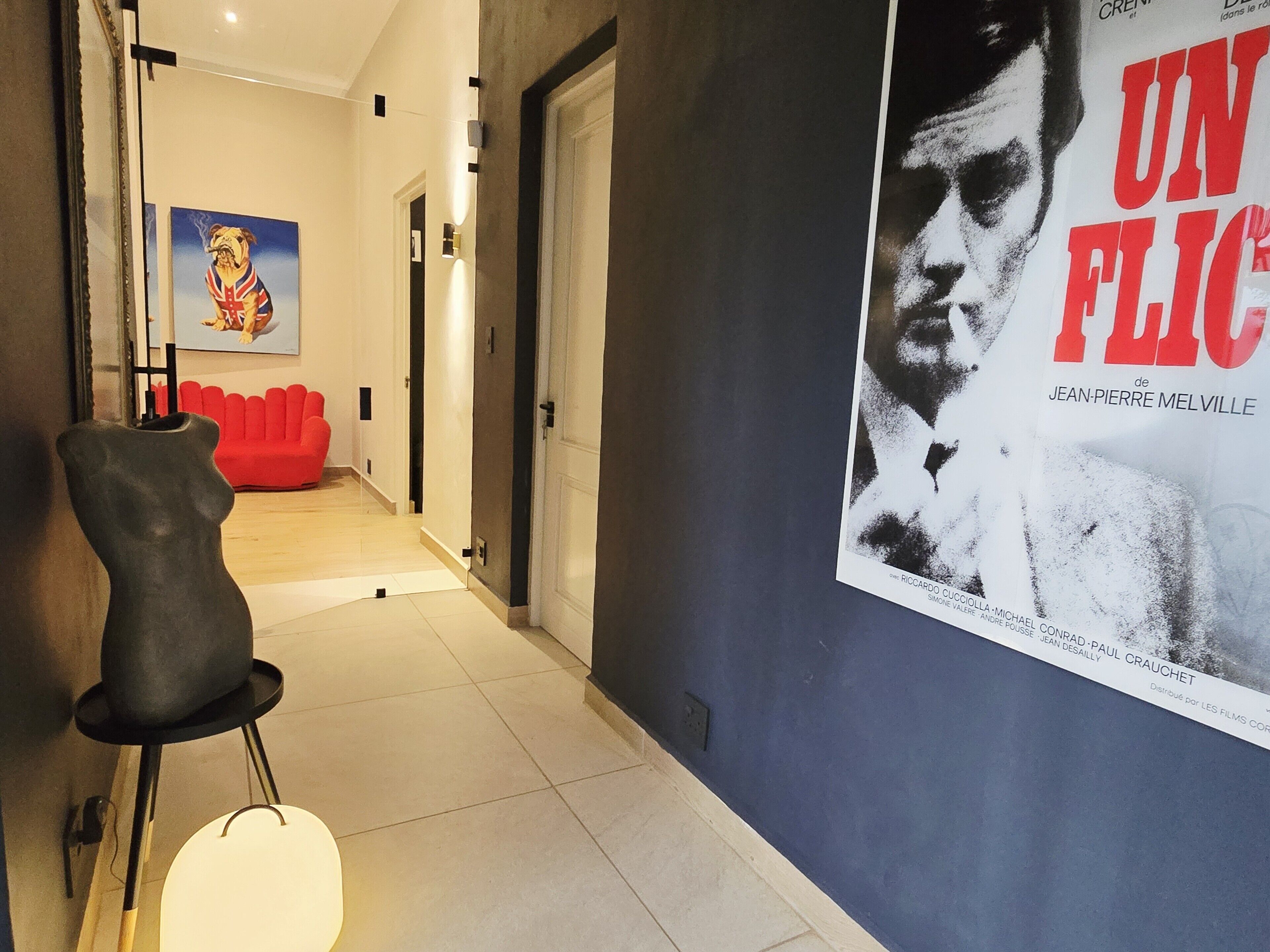 En gang med et filmplakat, en rød sofa og en skulptur.