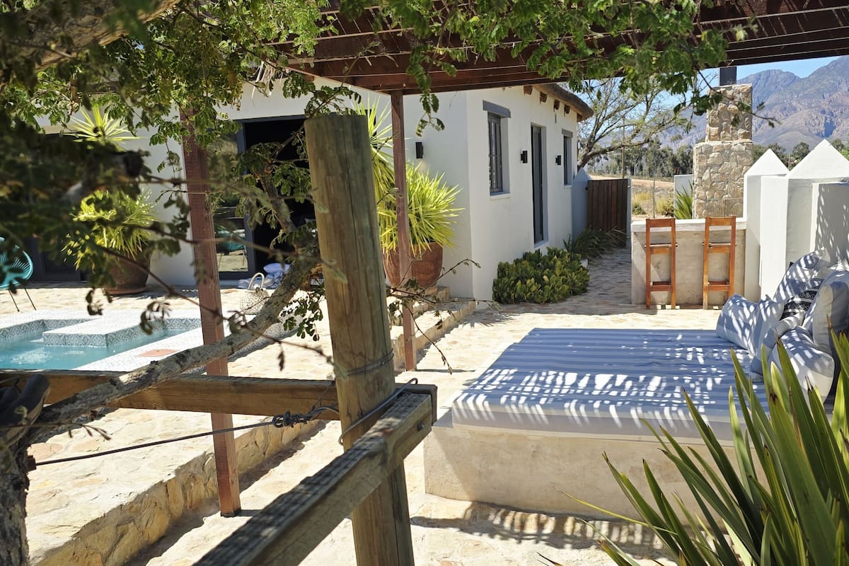 A pool area with a pergola, outdoor seating, and a view of mountains.