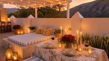 An outdoor dining area with a table set for two, candles, and a view of the mountains.