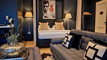 A modern bedroom with a bed, bedside lamps, a grey sofa, and a poster on the wall.