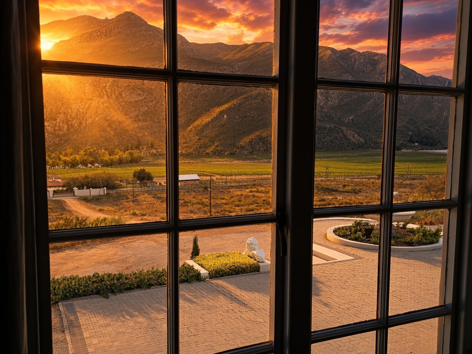 Une vue à travers une fenêtre, donnant sur un paysage de montagnes et de champs.