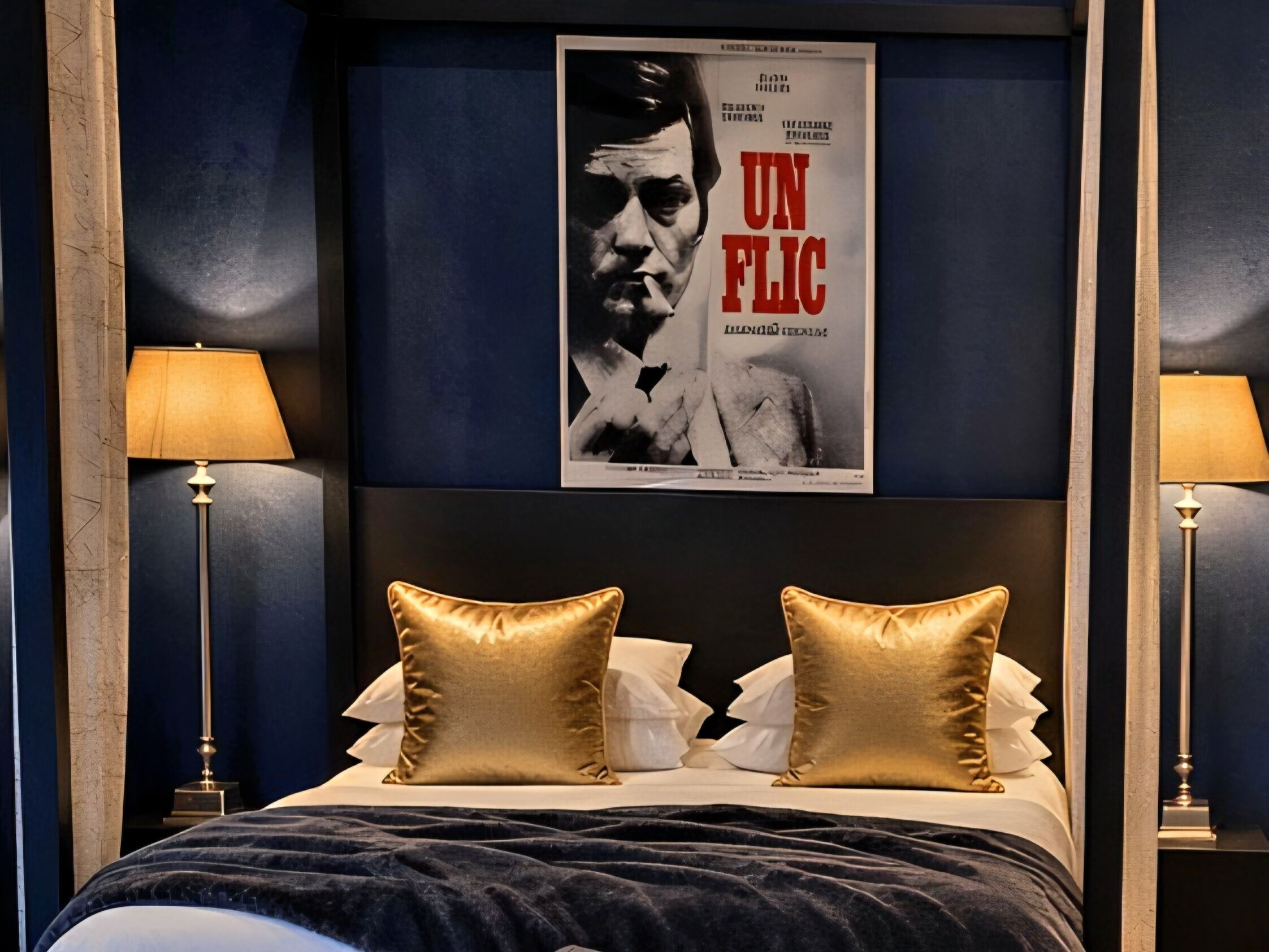 Ein Hotelzimmer mit einem großen Poster an der Wand, zwei Nachttischlampen und einem Bett mit zwei goldenen Kissen.