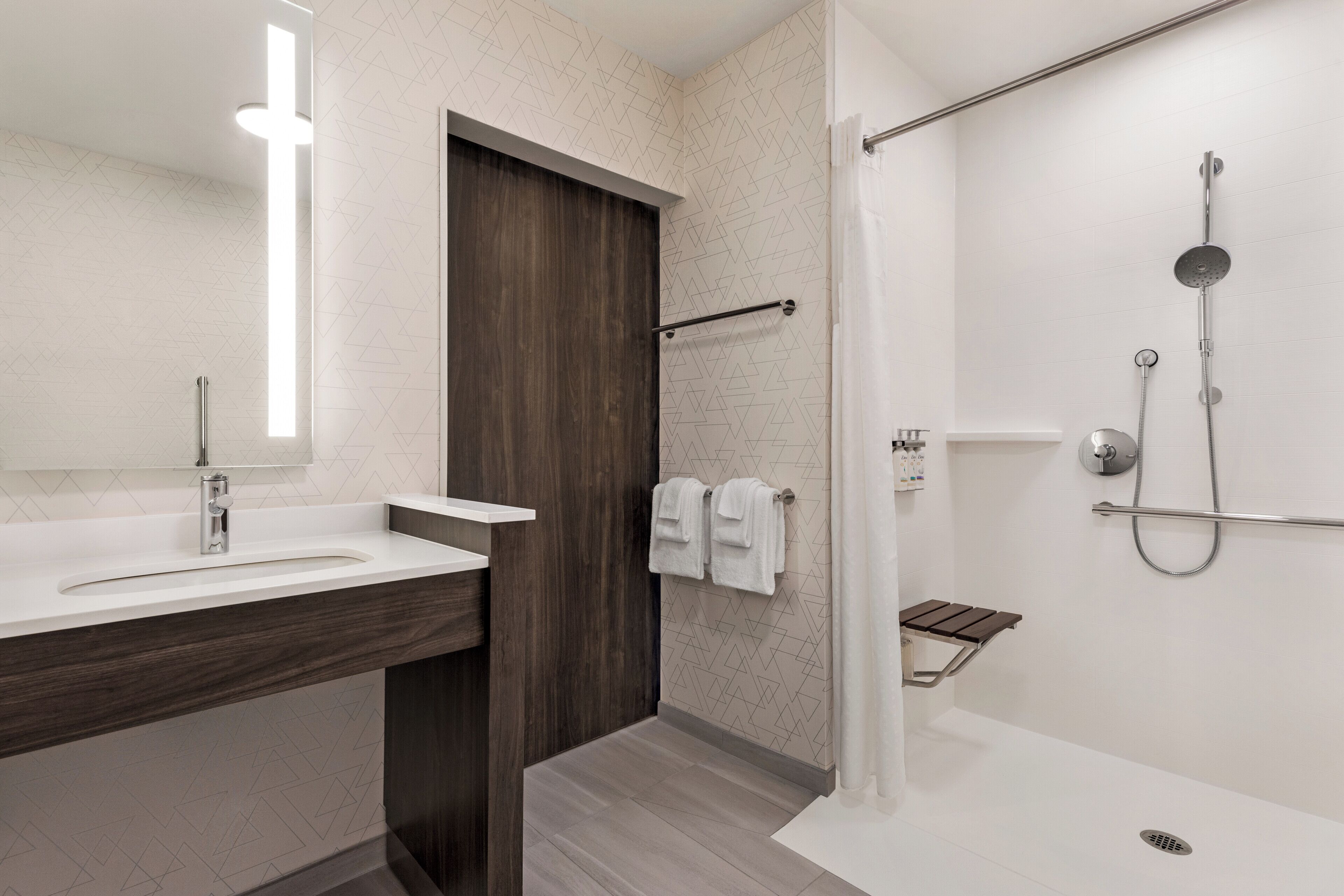 A modern bathroom with a wooden vanity, a shower with a handheld showerhead, and a towel rack.